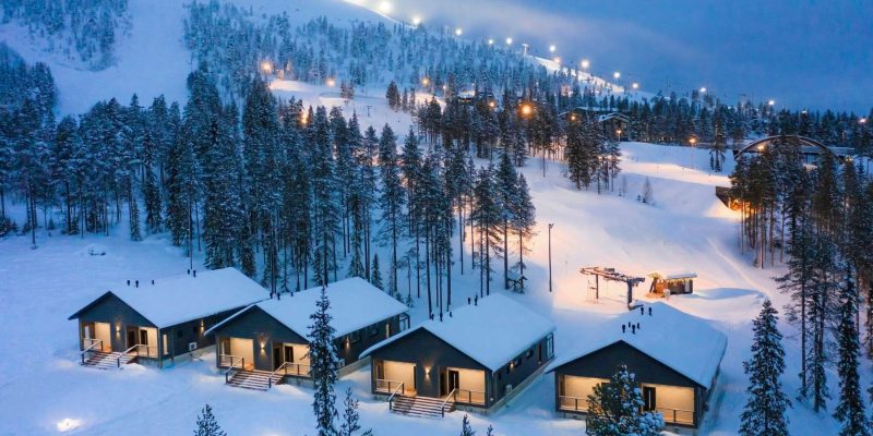 Pyhä in de winter met verlichte cabins met op de achtergrond skiliften en pistes